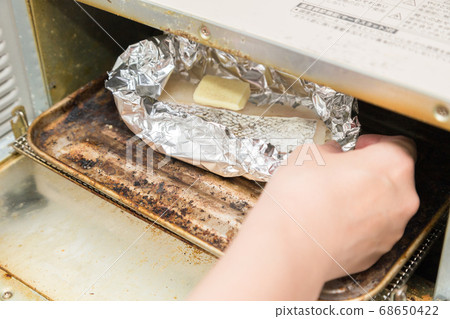 A woman's hand making a foil packet of cod 68650422