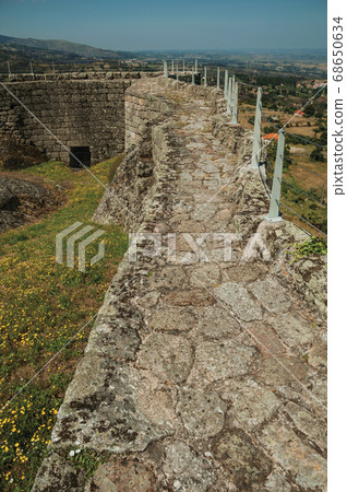 Pathway over stone wall around flowered courtyard Pathway over stone wall around flowered courtyard 68650634