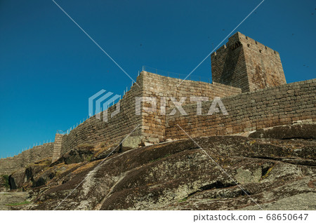 Stone wall and square tower from castle over rocky hill 68650647