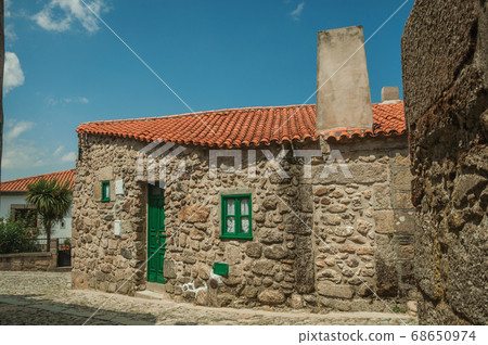 Old stone house with big chimney and wooden door 68650974