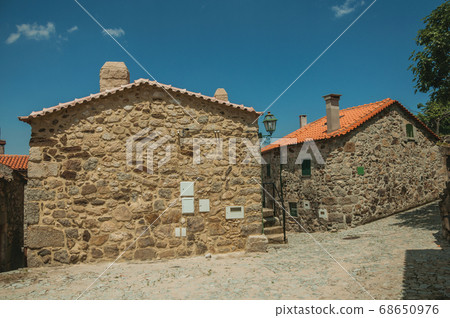 Cobblestone alley on slope and old stone houses 68650976
