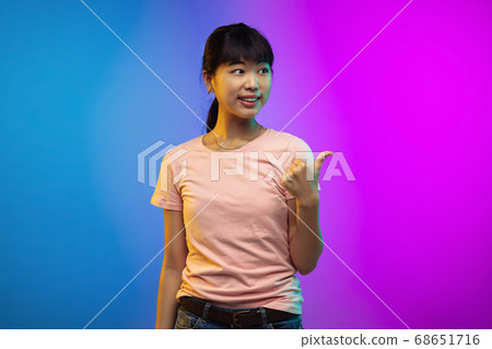 Asian young woman's portrait on gradient studio background in neon 68651716