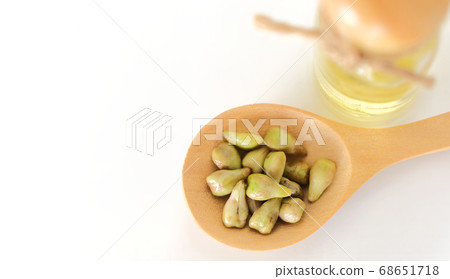 Top view of grape seeds in wooden spoon and blurred oil bottle on white background 68651718