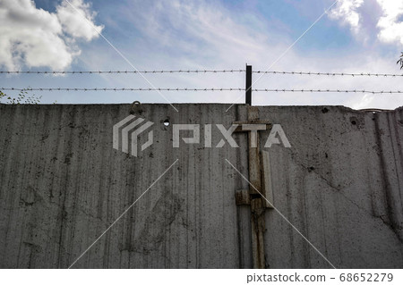 concrete fence with barbed wire against the blue sky 68652279