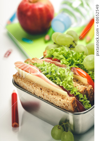 Lunch box with sandwich and fruits, school notebooks, stationery on white background Lunch box with sandwich and fruits, school notebooks, stationery on white background 68652549