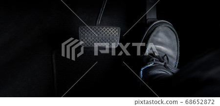 Man foot and accelerator and brake pedal inside the car or vehicle and copy space which black color leather shoe stepped on it for speed up or control automobile pace power. 68652872