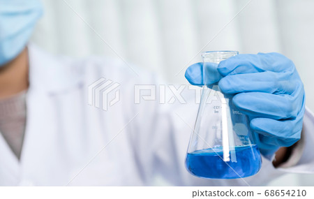 Scientists hold glass tube filled with blue chemical liquid for research and analysis in laboratory 68654210