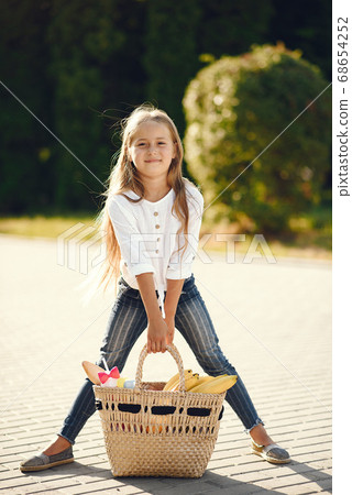 Little girl in a park standing with brown basket 68654252