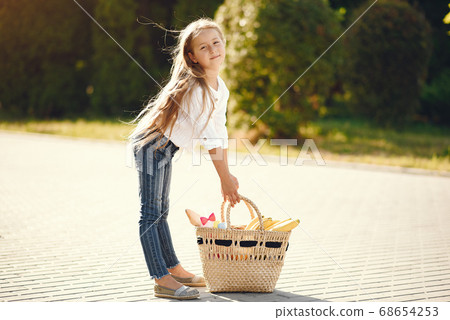 Little girl in a park standing with brown basket 68654253