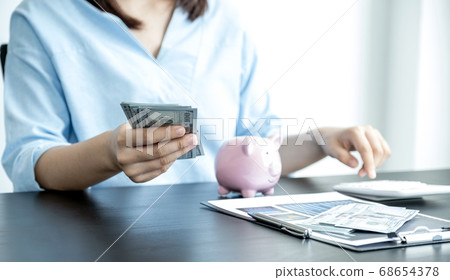 woman's hand holding dollar note and piggybank on table, Saving money for future plan and retirement woman's hand holding dollar note and piggybank on table, Saving money for future plan and retirement 68654378