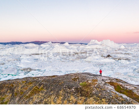 Greenland nature scenery landscape at sunset with hiking travel tourist walking enjoying view of frozen ice in ocean sea. Arctic adventure in the outdoors 68654970