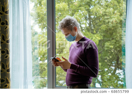 Young caucasian man wearing face mask while using Young caucasian man wearing face mask while using 68655799
