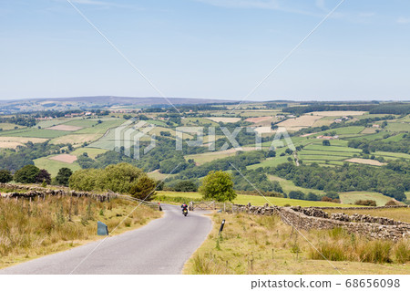 A motorbike travels along a country lane in the North York Moors National Park, England. 68656098