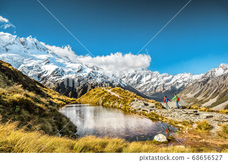 Hiking travel nature hikers in New Zealand. Couple people walking on Sealy Tarns hike trail route with Mount Cook landscape, famous tourist attraction Hiking travel nature hikers in New Zealand. Couple people walking on Sealy Tarns hike trail route with Mount Cook landscape, famous tourist attraction 68656527