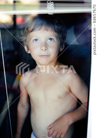 Little cute boy throught window making funny faces, home alone lifestyle concept 68657670