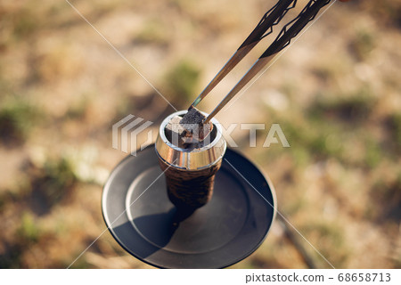 Cropped view of preparing tobacco for shisha on table outside 68658713