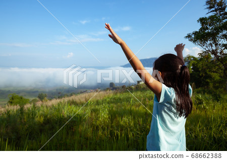 Asian child girl raise her arms looking at the beautiful mist and mountain 68662388