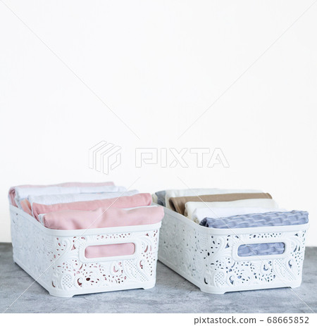 Two organizer boxes with pastel color clothes. Clothing neatly folded by method vertical storage "Konmari" 68665852