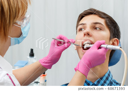 Female dentist is treating a patient tooth in 68671393