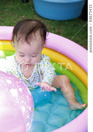 Baby playing pool in the garden 68673435