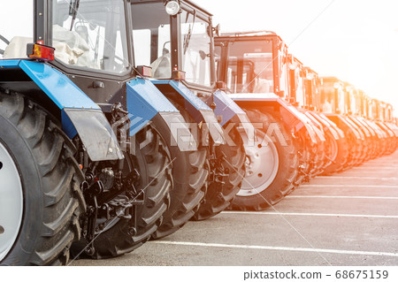 Many different tractors standing in row at agricultural fair for sale outdoors.Equipment for agriculture.Heavy industrial machines presented to an agricultural exhibition 68675159