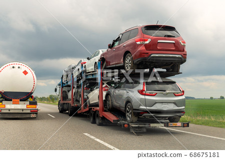 Tow truck car carrier semi trailer on highway carrying batch of damaged cars sold on insurance car auctions for repair and recovery. Vehicles shipment and rescue service Tow truck car carrier semi trailer on highway carrying batch of damaged cars sold on insurance car auctions for repair and recovery. Vehicles shipment and rescue service 68675181