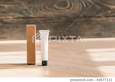 Cosmetic white tube and paper box on wooden table 68677132