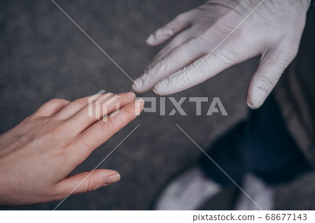 Two hands of a couple one in a plastic glove virus 68677143