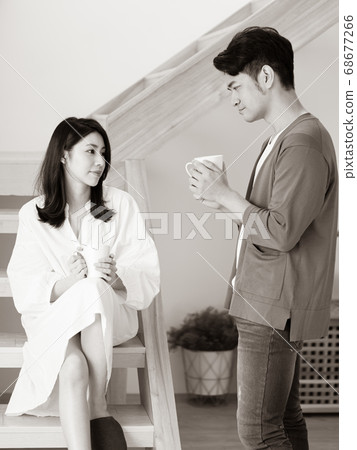 Young asian woman and man at home with cup of coffee in hands in black and white. Young asian woman and man at home with cup of coffee in hands in black and white. 68677266