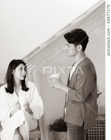 Young asian woman and man at home with cup of coffee in hands in black and white. 68677278