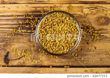 Fenugreek seeds in glass bowl on wooden table 68677551
