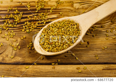 Fenugreek seeds in wooden spoon on wooden table 68677720