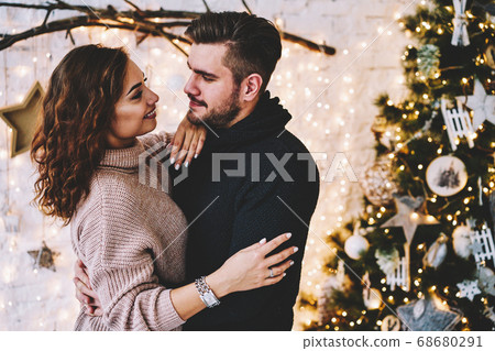 Happy caucasian couple in love having fun together near beautiful Christmas tree  68680291