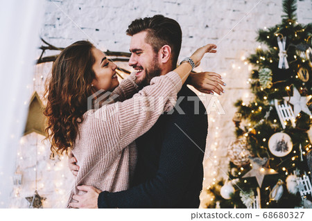 Happy caucasian couple in love having fun together near beautiful Christmas tree Happy caucasian couple in love having fun together near beautiful Christmas tree 68680327