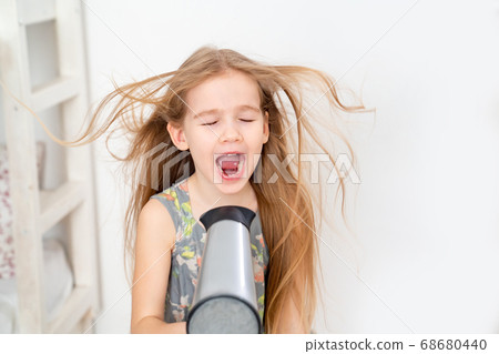 little girl drying her long hair with hair dryer little girl drying her long hair with hair dryer 68680440