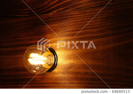 One incandescent lamp bulb over wooden surface One incandescent lamp bulb over wooden surface 68680513