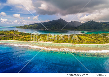 Aerial French Polynesia luxury travel honeymoon destination. Beach vacation at motu island of Huahine, Tahiti, Oceania adventure. View from above of paradise, French Polynesia, South Pacific Ocean. 68680627