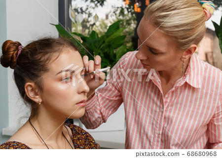 The process of creating makeup. Makeup artist working with a brush on the face of the model. 68680968