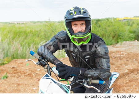 A man in motorcycle equipment sits on an enduro motorcycle. 68680970