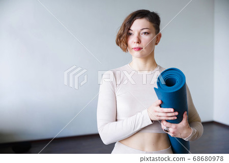 Beautiful girl getting ready for yoga indoors in daylight. Beautiful girl getting ready for yoga indoors in daylight. 68680978
