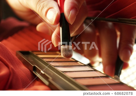 採取與一把刷子的女性手顏色從眼影膏。 (總圖) 採取與一把刷子的女性手顏色從眼影膏。 (總圖) 68682078