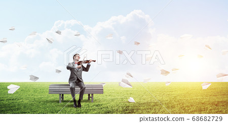 Handsome violinist in park on wooden bench play his melody 68682729