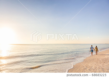 Beach relaxing vacation - travel tourists couple walking on beach at sunset landscape background. Summer holidays destination Beach relaxing vacation - travel tourists couple walking on beach at sunset landscape background. Summer holidays destination 68683223