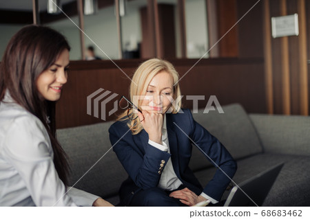Close up of two serious employees co-working on line with a laptop at office 68683462
