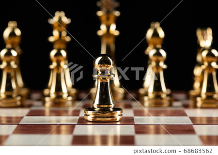 Golden chess figures standing on chessboard Golden chess figures standing on chessboard 68683562
