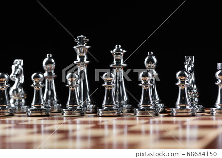 Silvery chess figures standing on chessboard 68684150
