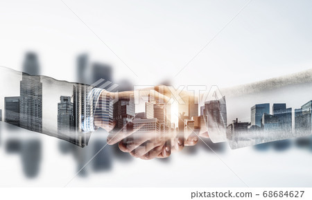 Business handshake as idea for unity and cooperation or greeting. Mixed media Business handshake as idea for unity and cooperation or greeting. Mixed media 68684627