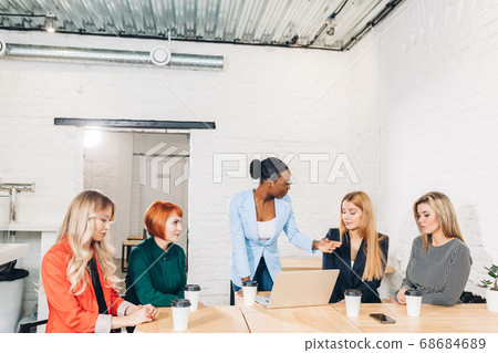 African female boss telling off her female employees, sitting in meeting room. African female boss telling off her female employees, sitting in meeting room. 68684689