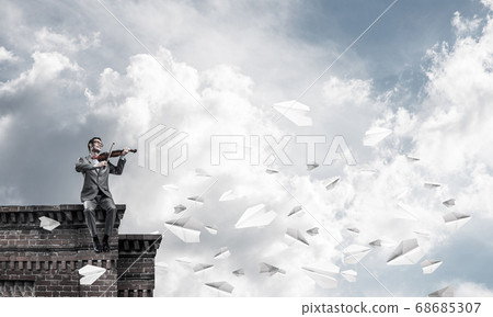 Handsome businessman play his melody and paper planes fly around Handsome businessman play his melody and paper planes fly around 68685307