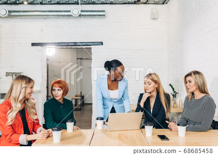 African female boss telling off her female employees, sitting in meeting room. African female boss telling off her female employees, sitting in meeting room. 68685458